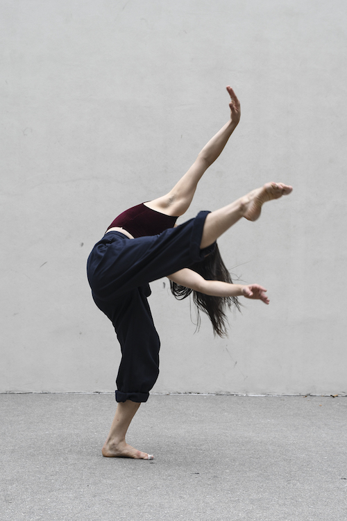 A woman kicks her leg in the air so that her head lower than her torso.