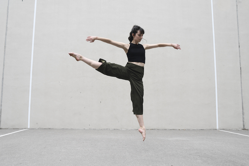 A woman leaps into the air with one leg extended out to the side.