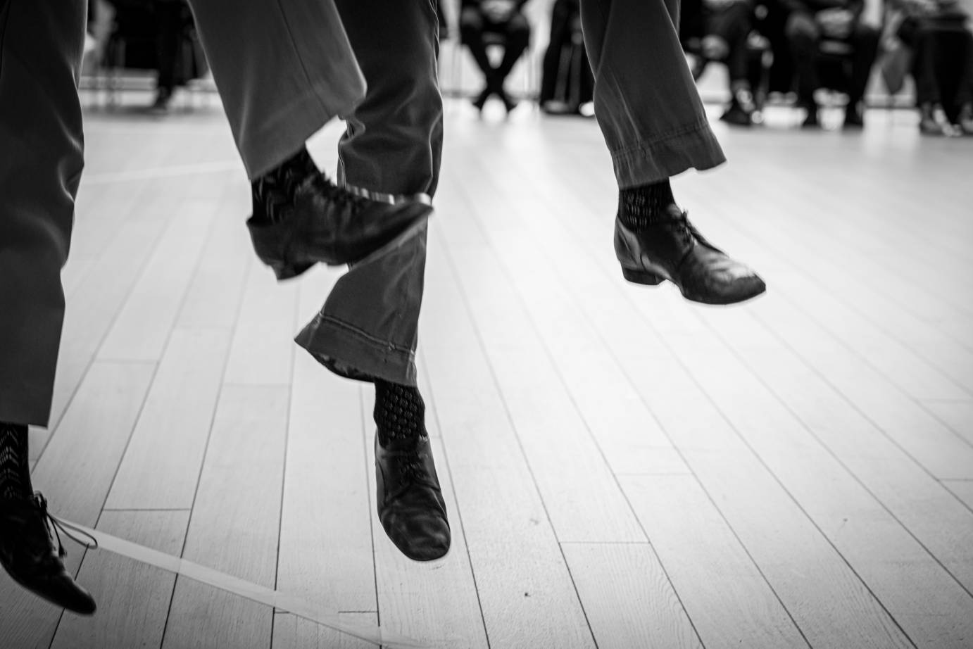 Pictured are booted feet and lower legs jump off the wooden slatted floor.