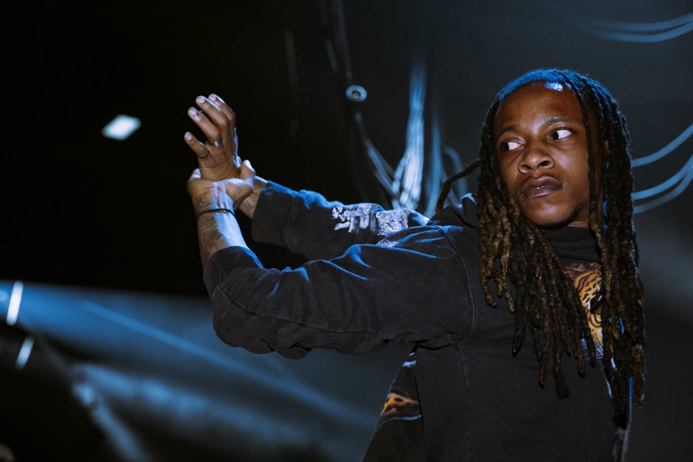 A Flexn dancer looks back at their extremely flexed arms behind their back.