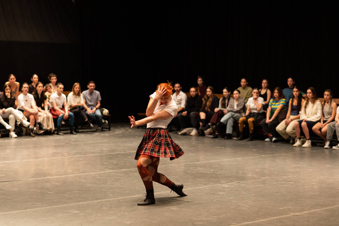 female dancer solo in middle of performance space in a twisted shape