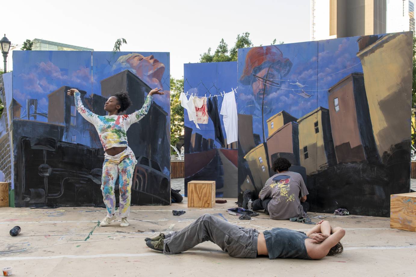 2 city scape paintings behind 2 dancers, one prone, one standing arms in V