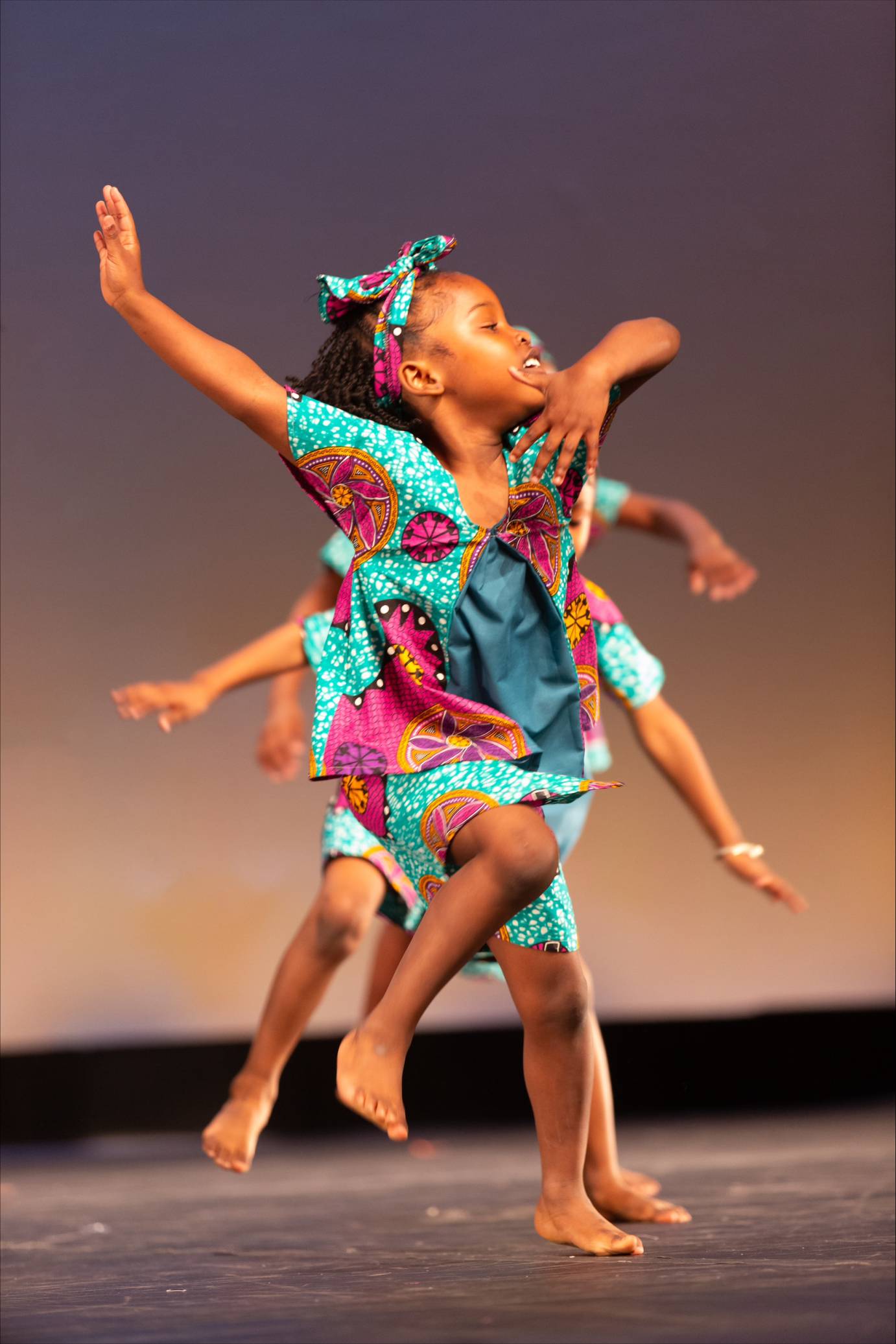 child dancer in bright blue pattern costume skipping into the air