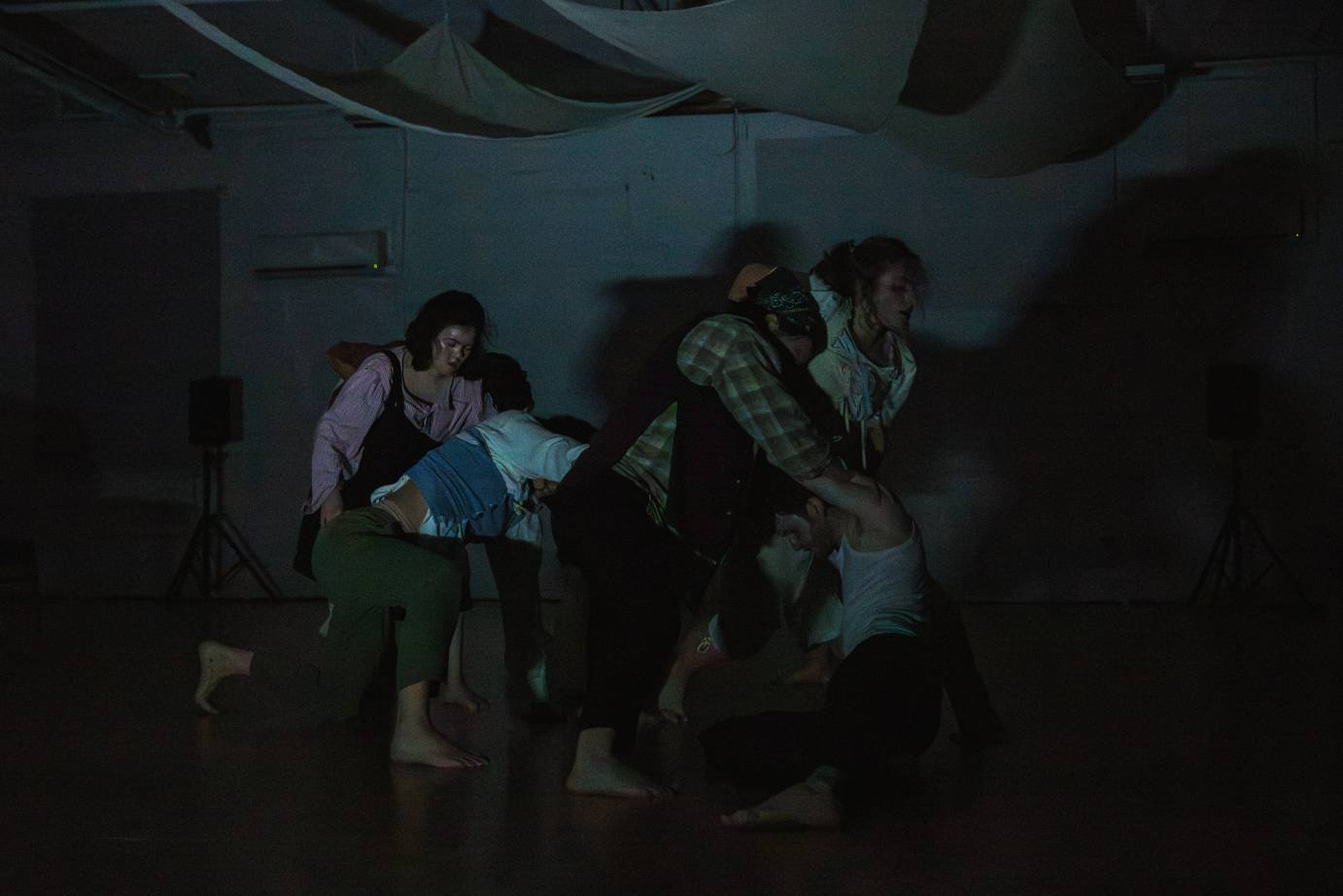 Dancers close together facing the same direction in a dim light.