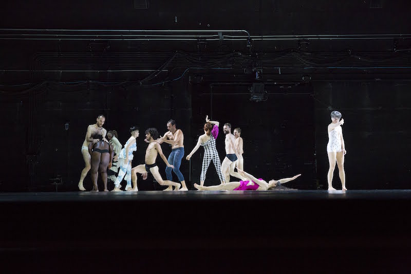 A group of dancers in a big tableau. A dancer in a magenta gown lays on the floor