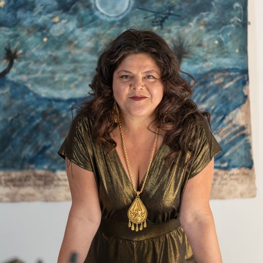 woman with long thick hair and red lipstick gazes out towards viewer 