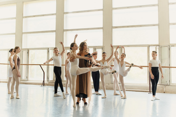 Kateryna Kukhar dressed elegantly in a gown and heels guiding her young student in the Ukraine. a not so casual, casual shot.