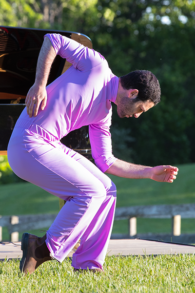 Or Shraiber, the man in pink, stands in a crouched profile, in one section of his improvisation.