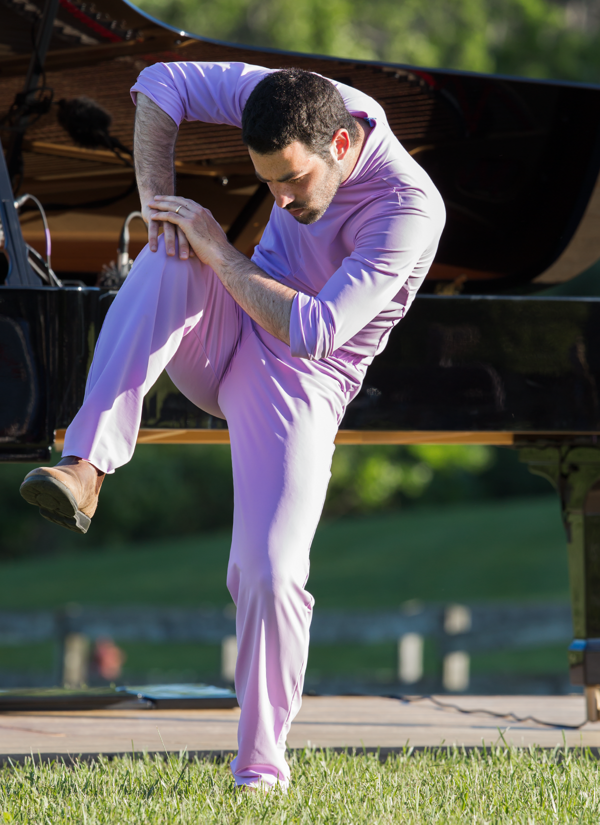 Or Shraiber, the man dressed in pink, balances on one leg, with his body bent towards his non-weighted bent leg. His concentration is intense.