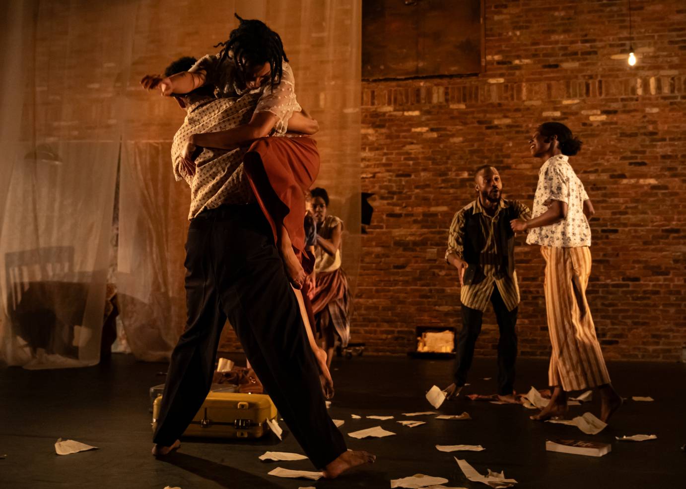 A man holds a woman in a lift while three figures stand alert in the background.