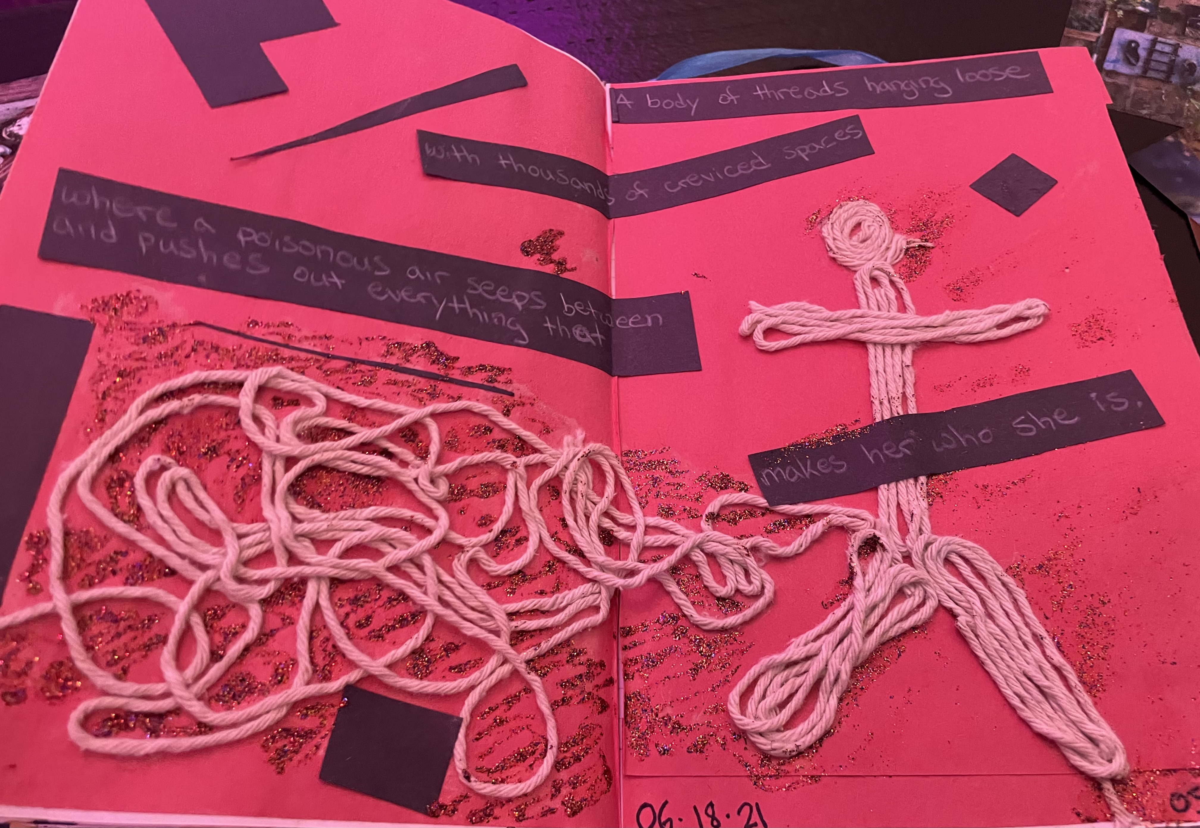 photo of a simple collage black shapes with words, pasted on red paper with a figure made out of pink yarn pasted to the right with her/his/their body (yarn) unfurling to the left 