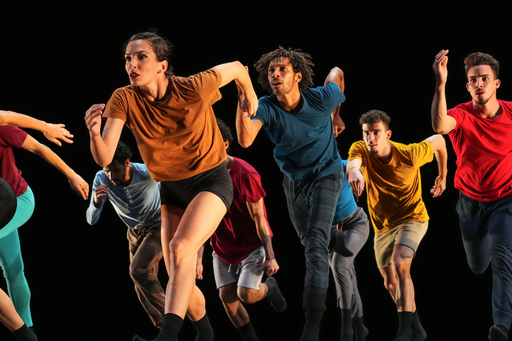 the company running forward wearing tops and shorts in bright colors with eager expectant and engaged faces excited to get to their destination 