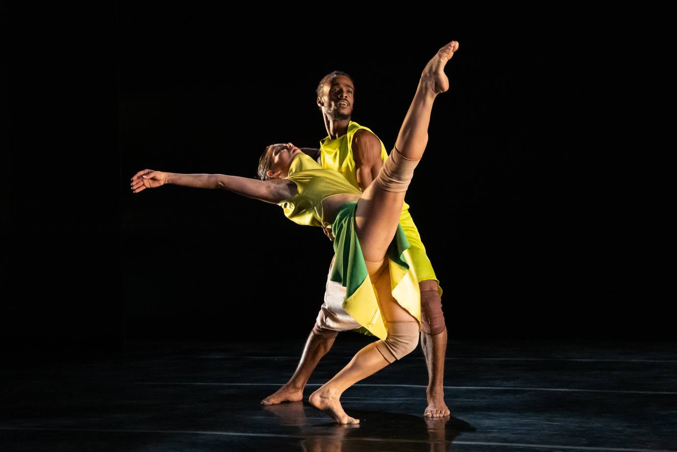 A man holds up a falling woman whose leg extends upward.