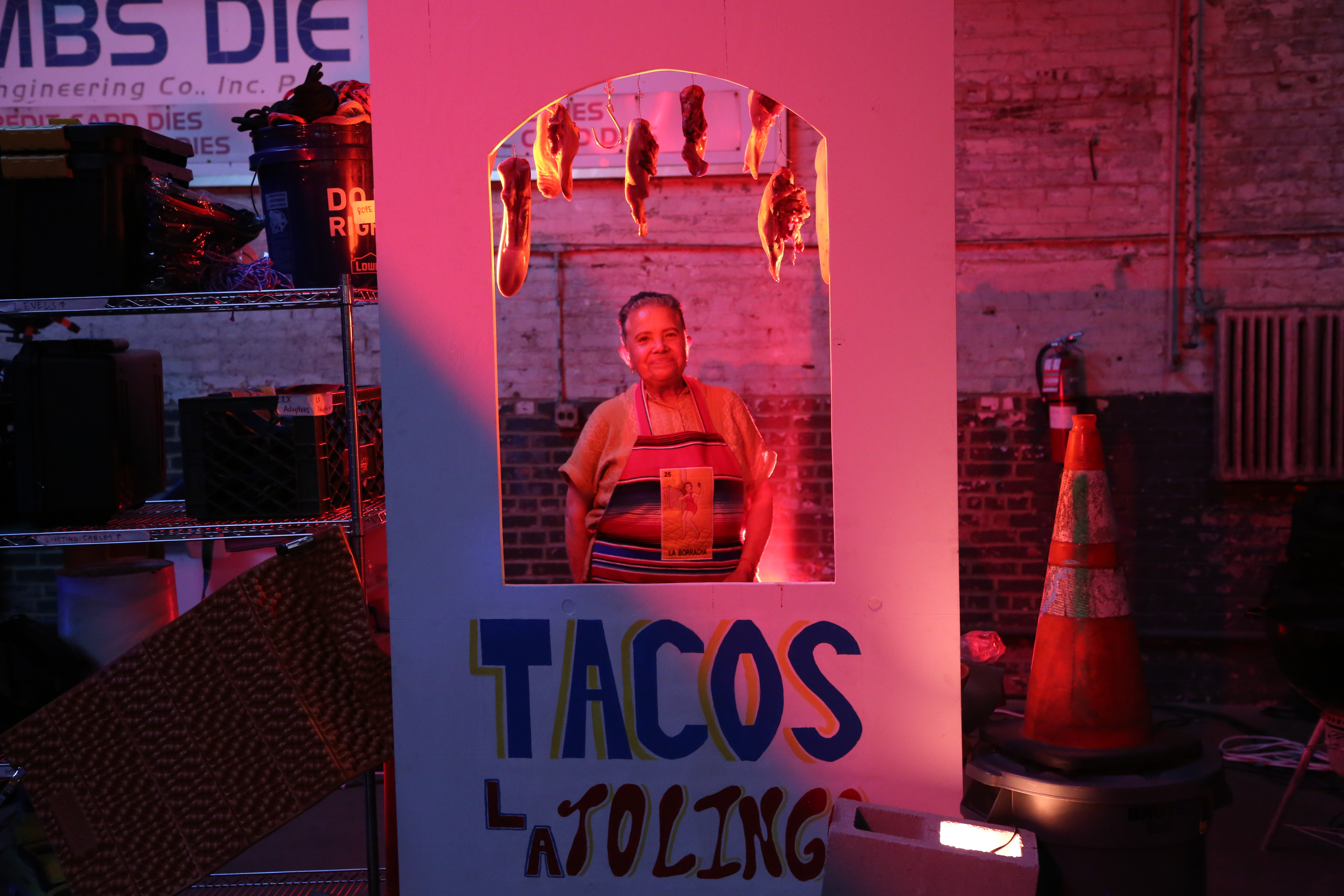 A taco stand freestands with a man situated in the window-like opening.
