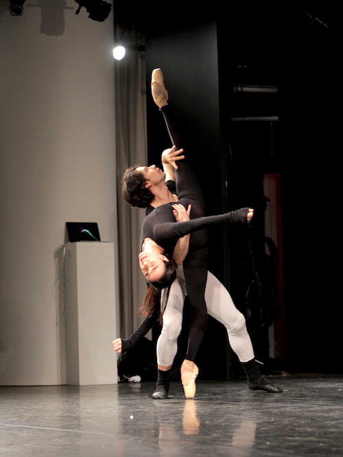 Herman Cornejo supports Alessandra Ferri in a back bend. She raises one leg high in the air as her head reaches toward the ground.