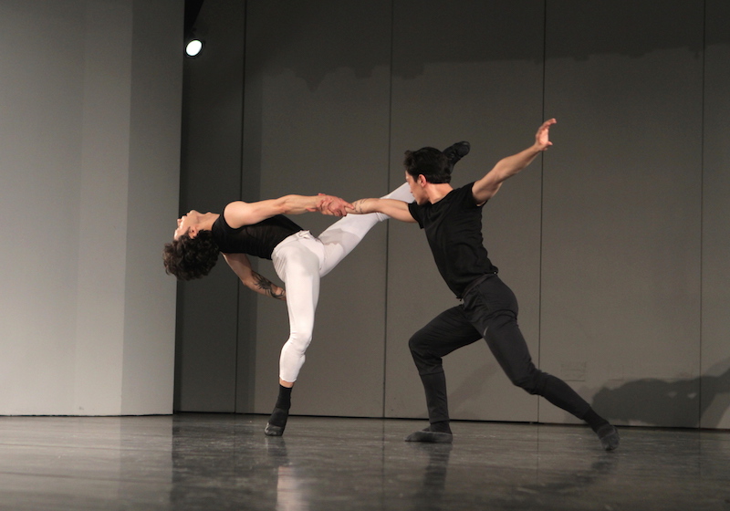 Jeffrey Cirio hands Herman Cornejo as he arches his back and extends one leg into the air.