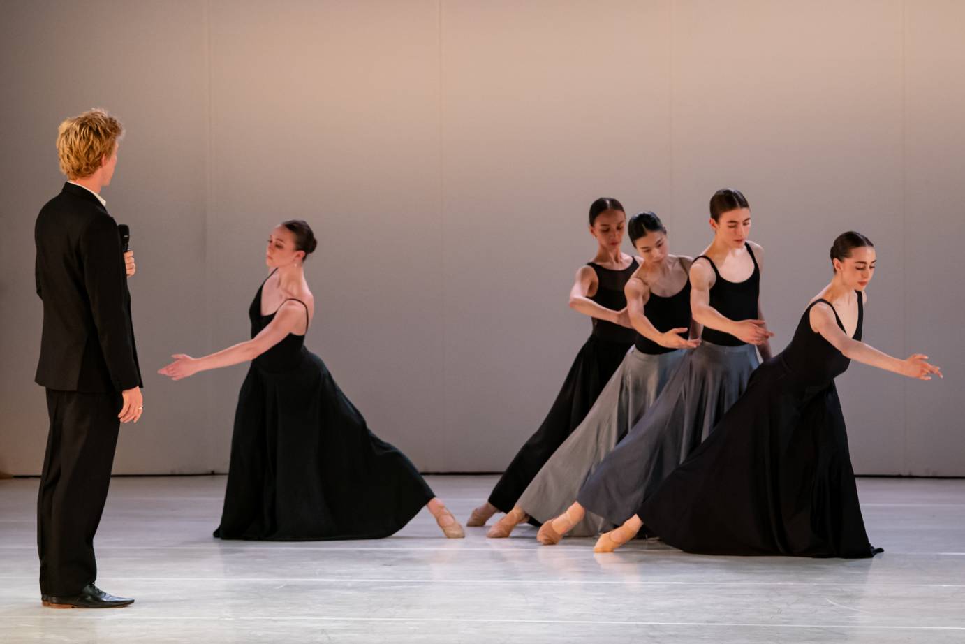 Blond-headed Ball watches his five dancers, one woman soloist and four dances lined up on the diagonal, all reaching their right arms pelvis high.