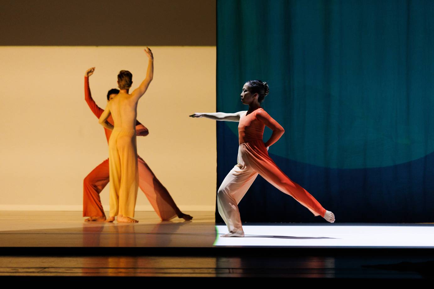 A trio of two men and one woman: The men are upstage facing one another while the woman is downstage of them facing stageright lunging with the right arm horizontal.