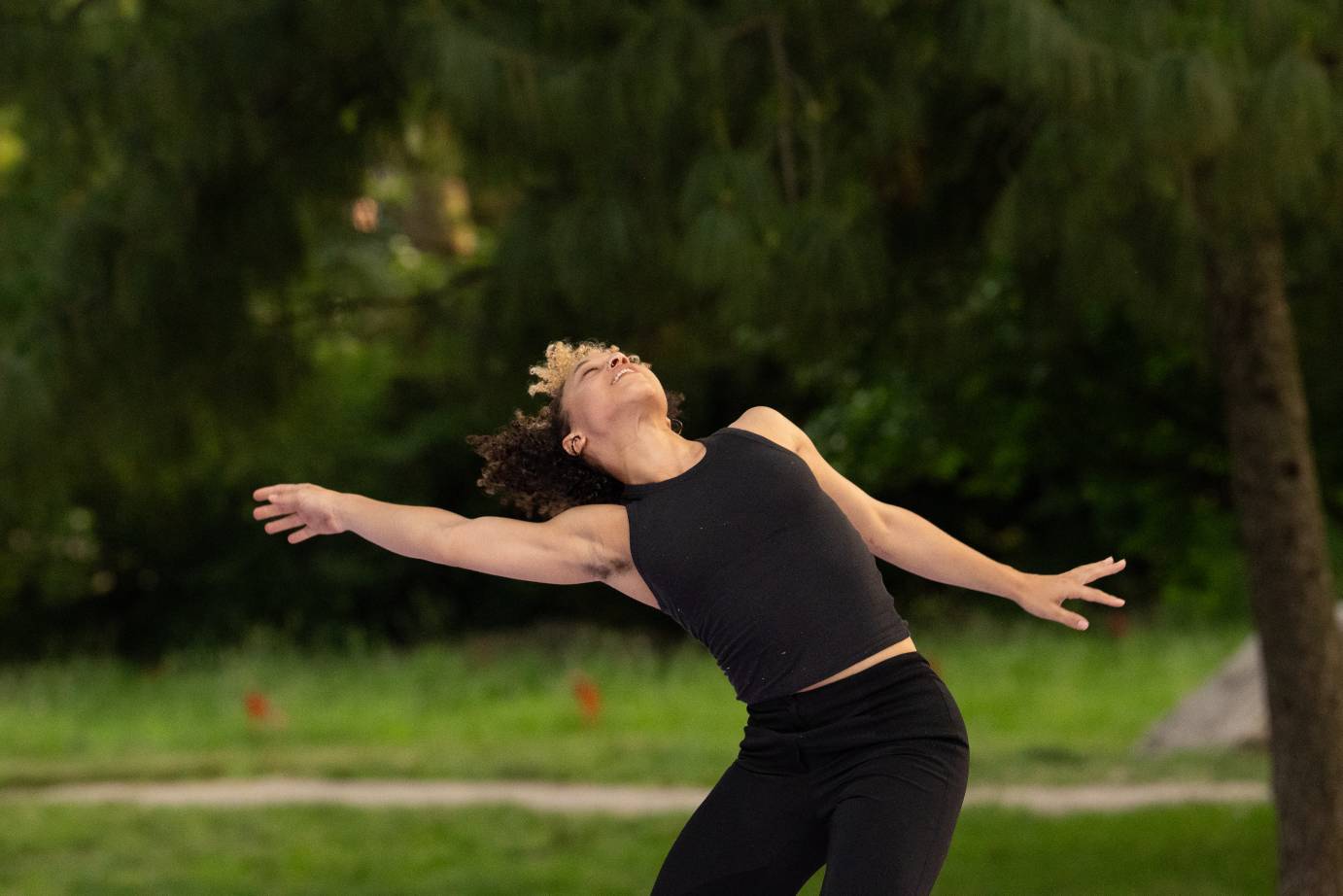 Woman in the woods with outstretched arms, leaning back