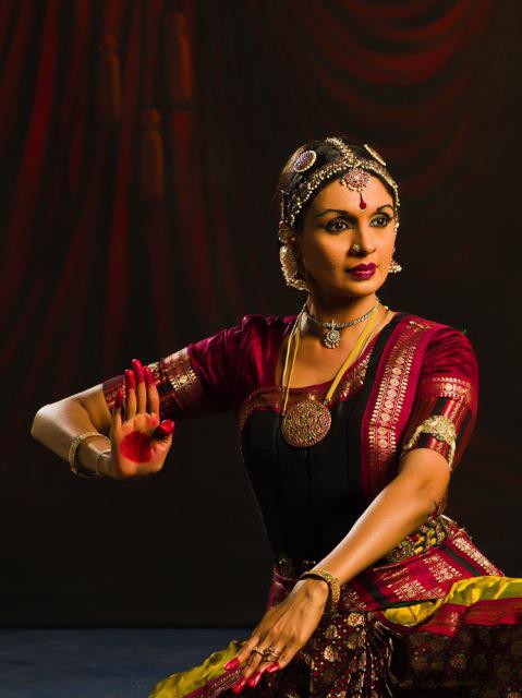 A red-lipped woman dressed in red flexes her right hand with a red-painted palm open to the audience