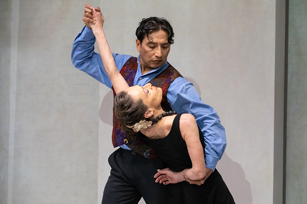 a couple in the midst of a social dance a man portraying Diego Rivera dips his female partner  who is portraying Frida Kahlo 