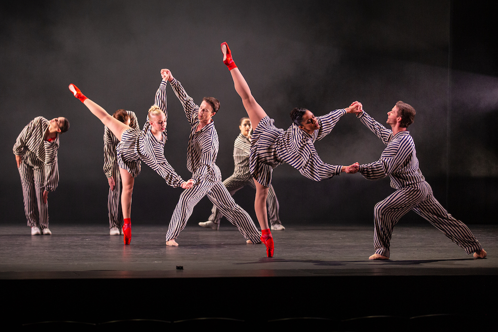 cast of dancers wearing iterations of black and white striped outfits