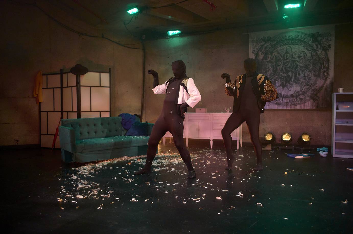 two faceless figures totally covered in all encompassing full body unitards pose in a disheveled space...